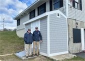 Two men standing beside a shed
