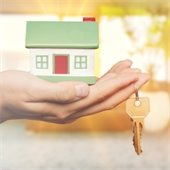 Hand holding a small house model with a key