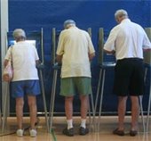 Three people at portable voting booths