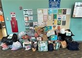 Donated goods piled in front of a bulletin board inside the Chatham Community Center