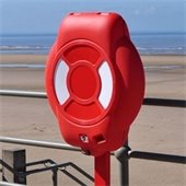 Orange circular cabinet mounted on a railing at a beach
