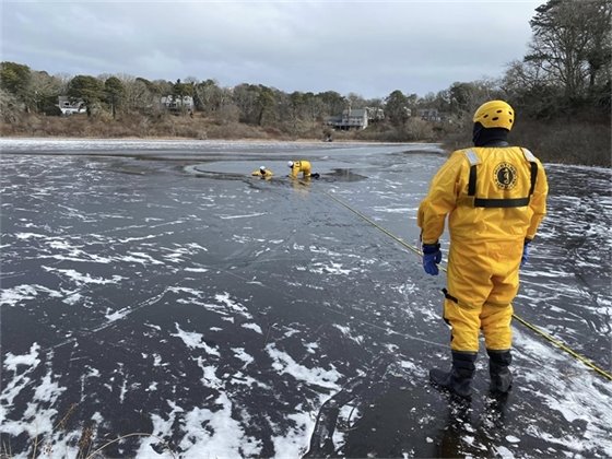 People in yellow survival suite training on a partially frozen pond