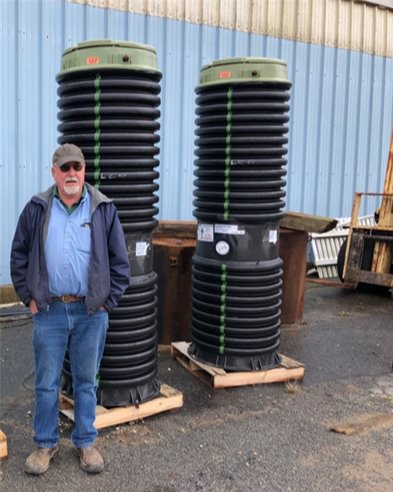 A man standing beside two black grinder pumps