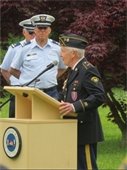 Man in uniform at podium with men in Coast Guard uniform behind him