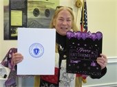 Dale Kelley holding her retirement card and a citation from the commonwealth on the day of her retirement