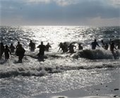 Backlit picture of people jumping into the ocean