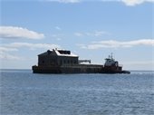 Wooden structure on a barge being towed by a tug boat