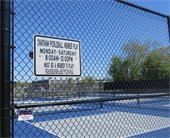 Outdoor pickleball courts within a black chain link fence