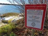 Dinghies on a beach next to a red sign noting when watercraft need to be removed from the area
