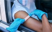 Person seated in a car receiving a vaccination through the car window