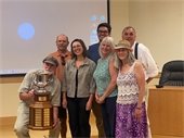 Group of people smiling at the camera holding a trophy