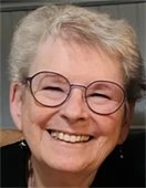 A woman with short grey hair smiling broadly at the camera