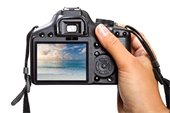 Woman's hand holding a camera displaying a beach scene
