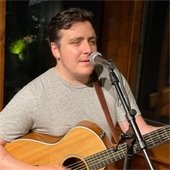 Matt Hamilton playing an acoustic guitar singing into a microphone
