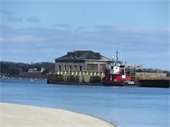 Wooden structure on a barge being towed by a tug boat