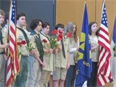 Scouts holding flags and red poppies in a gymnasium
