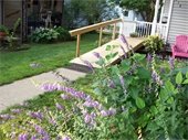 A wheelchair ramp leading to a white porch with flowers along the path