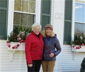 Two women standing in front of window boxes decorated for the holidays