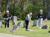 Women placing US flags at gravesites