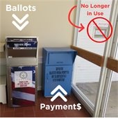 A red, white and blue ballot drop box and a blue payment drop box in a vestibule.