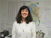 Woman shoulder length brown hair standing in front of a zoning map smiling