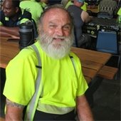 Brian Powers in a Hi Vis shirt seated at a picnic table at the Department of Public Works