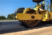 Large yellow roller truck on fresh black asphalt