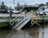 Wooden platform adjacent to a bulkhead with metal stairs leading down into the water