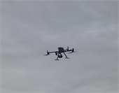 Radio controlled drone flying against a gray sky
