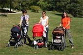 Three young women pushing strollers in a park