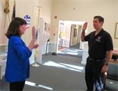 Woman with dark hair in a blue shirt swearing in a firefighter.
