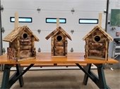 Three owl houses made from natural wood displayed on a table.