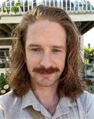 Man with shoulder length brown hair and mustache