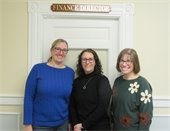 Three women standing in front of a door with Finance Director sign above it