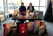 Two women standing behind a table piled with donated pet food