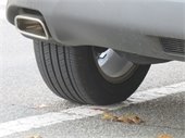 Rear tire of a gray vehicle parked outside a white parking space line