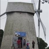 A wooden windmill with its side door open and several people standing at the entrance