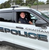 Officer Kenton Frenking sitting in the passenger seat of a Chatham Police cruiser smiling out the window