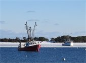 Two fishing boats on moorings in a harbor one in clear water and the other surrounded by ice