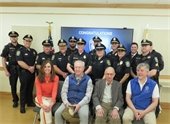 Officer Thompson standing with members of the department with Town officials seated in front