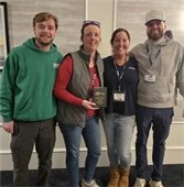 Four members of the Recreation and Beaches staff standing holding a wooden placque