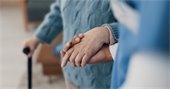 Hand holding hand of person walking with a cane