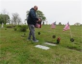 A man placing flags on graves