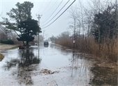 A flooded street with a car driving through it