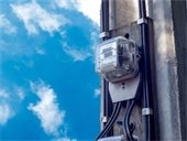 Electric meter mounted on the corner of a structure with blue sky