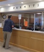 Man standing at a counter with PERMITS written out above the service window
