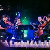 Quartet of String Musicians playing on a stage lined with candles