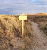 Caution sign on a beach regarding hunting activities