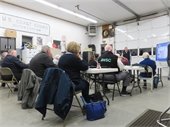 Members of Chatham's Municipal Academy seated at folding table in the Harbormaster's workshop