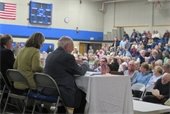 Members of the Select Board seated at a table in profile in from of audience at Annual Town Meeting